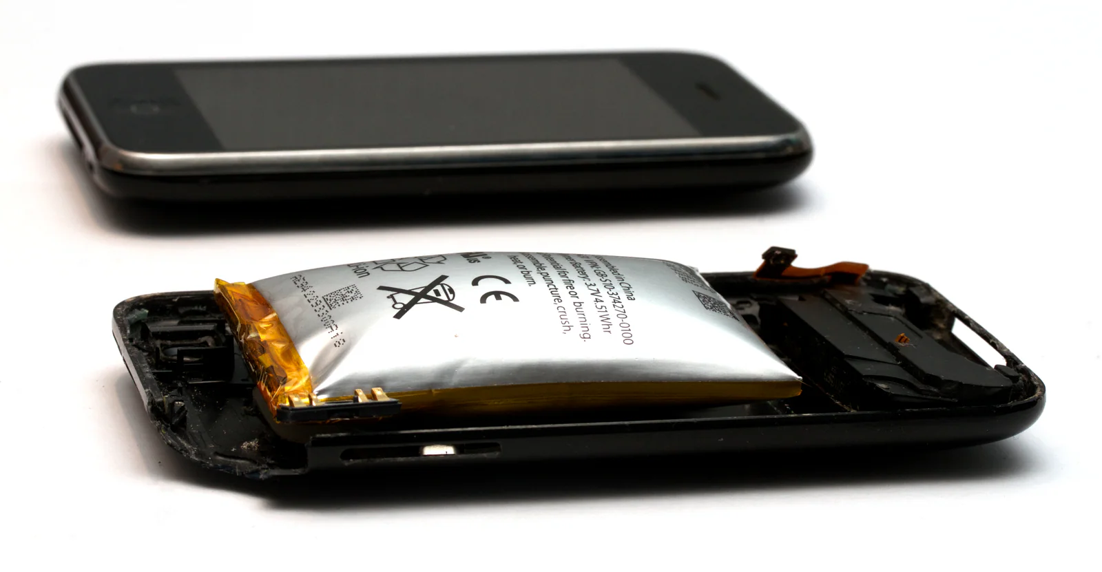 вздувшийся литий-полимерный аккумулятор внутри iPhone 3GS рядом с исправным смартфоном
